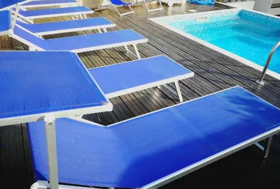 a row of blue benches next to a swimming pool at B&B Il Sole in Castelluzzo