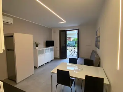 a living room with a table and chairs and a kitchen at Casa Penelope in Mondello