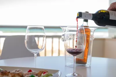 a bottle of wine is being poured into a glass at La perla sulla spiaggia in Alcamo Marina