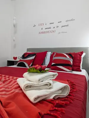 a bed with red sheets and white towels on it at I colori della Sicilia in Cinisi