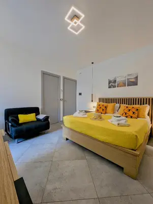 a bedroom with a large yellow bed and a couch at I colori della Sicilia in Cinisi