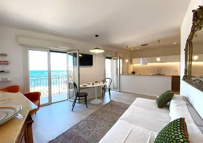 a living room with a white couch and a kitchen at Solemar Sicilia - Casa Tosca in Ficarazzi