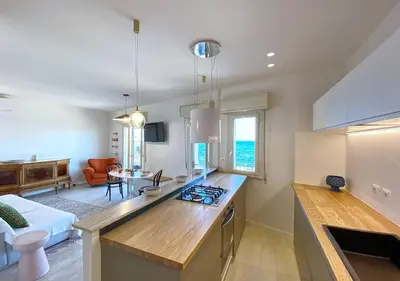a kitchen with a counter top and a living room at Solemar Sicilia - Casa Tosca in Ficarazzi