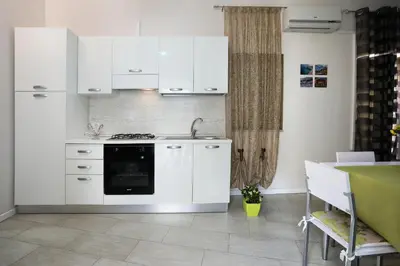 a kitchen with white cabinets and a stove top oven at Casa Le Nereidi in Castellammare del Golfo