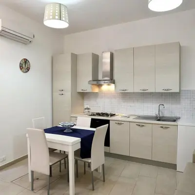 a kitchen with a table and a kitchen with white cabinets at Casa Le Nereidi in Castellammare del Golfo