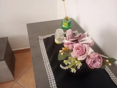 a table with a vase of flowers and a candle at L' Arco Antico in Palermo