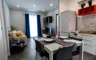 a kitchen and living room with a table and chairs at NIKA NIKA Holiday House in Carini