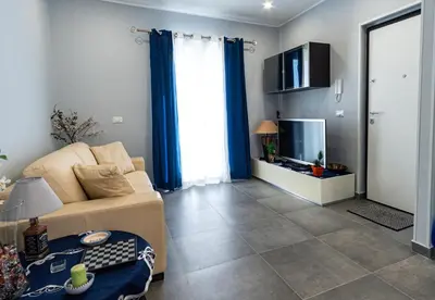 a living room with a couch and a flat screen tv at NIKA NIKA Holiday House in Carini