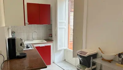 a small kitchen with red cabinets and a window at Residenza Cattedrale in Palermo