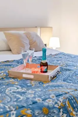 a tray with a bottle of wine and glasses on a bed at Lascaris 11 in Palermo