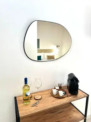 a mirror on a wall above a wooden table with wine glasses at 4Rooms in Palermo