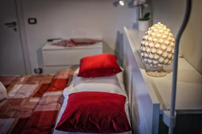 a room with a bed with red sheets and a lamp at Il Bel Canto - Suite in centro storico in Palermo