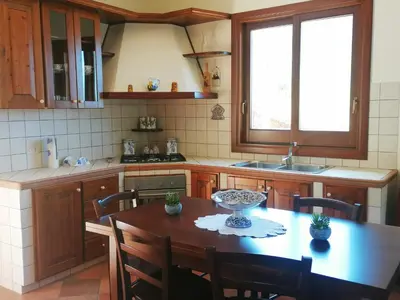 a kitchen with a wooden table with chairs and a tableablish at Villa Francesca in Castelluzzo