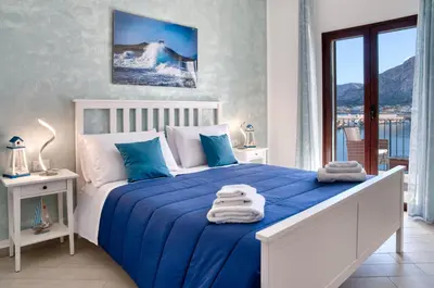 a bedroom with a blue and white bed and a balcony at Vista Mare Rooms in Isola delle Femmine