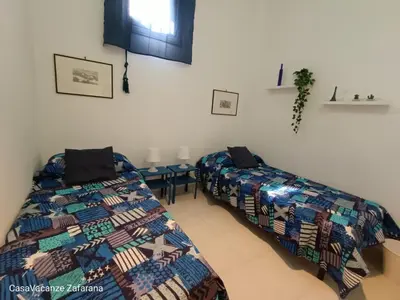 a bedroom with two beds and a table at Casa Vacanze Zafarana in Santa Flavia