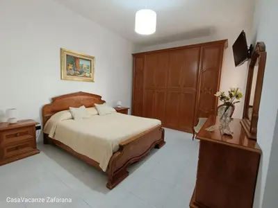 a bedroom with a bed and a wooden cabinet at Casa Vacanze Zafarana in Santa Flavia