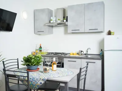 a kitchen with a table with chairs and a refrigerator at Isola delle Femmine - Casetta del Pescatore in Isola delle Femmine