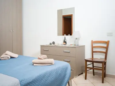 a bedroom with a bed and a dresser and a chair at Isola delle Femmine - Casetta del Pescatore in Isola delle Femmine