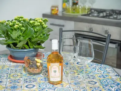 a bottle of alcohol sitting on a table with two wine glasses at Isola delle Femmine - Casetta del Pescatore in Isola delle Femmine