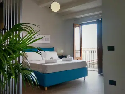 a bedroom with a blue bed and a plant at Ponticello Apartments in Palermo
