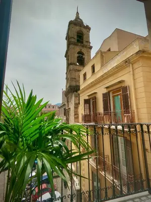 a building with a clock tower behind a fence at Ponticello Apartments in Palermo
