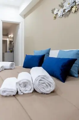 a bed with blue pillows and white towels on it at ARIA b&b in Terrasini