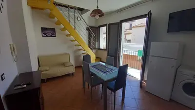 a living room with a table and chairs and a staircase at A casa scalilla 2 in Palermo