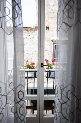 an open door to a balcony with a table with flowers at Noble Suite in Palermo