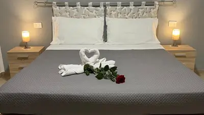 a bedroom with a bed with two towels and two roses at Cuba Holiday House in Palermo