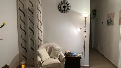 a living room with a chair and a clock on the wall at Cuba Holiday House in Palermo