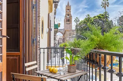 a table on a balcony with a view of a church at Behind the Cathedral apt in Palermo