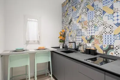 a kitchen with a counter with two chairs in it at Roccella Apartments in Palermo