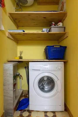a washing machine in a laundry room with shelves at Casa Joya Apartment in Isola delle Femmine