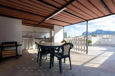 a table and chairs on a balcony with a kitchen at Casa Joya Apartment in Isola delle Femmine