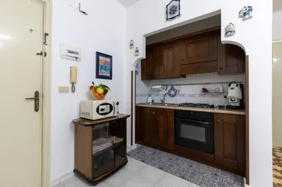 a kitchen with wooden cabinets and a microwave at Casa Joya Apartment in Isola delle Femmine