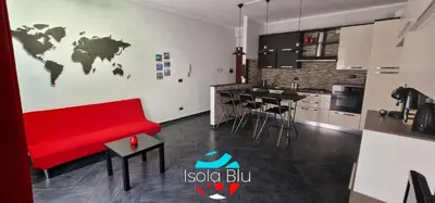 a living room with a red couch and a kitchen at Isola Blu Casa a pochi passi dal mare in Isola delle Femmine
