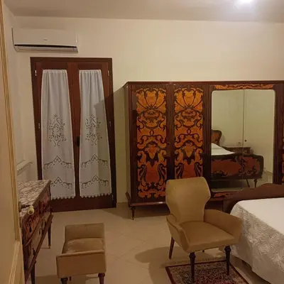 a bedroom with a bed and a chair and a mirror at Casa vacanza Acquanuova in Calatafimi