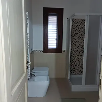 a white bathroom with a toilet and a window at Casa vacanza Acquanuova in Calatafimi