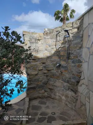 a shower in a stone wall next to a swimming pool at Casa Anna in Carini