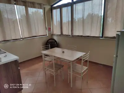 a table and chairs in a room with windows at Casa Anna in Carini