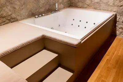 a bath tub in a bathroom with a stone wall at Five suite in Palermo