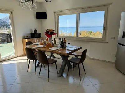 a dining room with a table with chairs and a large window at Mondello Luxury Apartment in Palermo