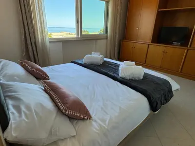 a bedroom with a large bed with a large window at Mondello Luxury Apartment in Palermo