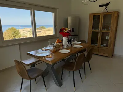 a dining room table with chairs and a large window at Mondello Luxury Apartment in Palermo