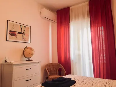 a bedroom with red curtains and a bed with a chair at Apartment 