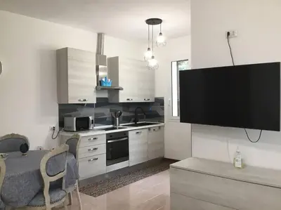 a kitchen with a tv on the wall and a table at Casa Amuri in Scopello