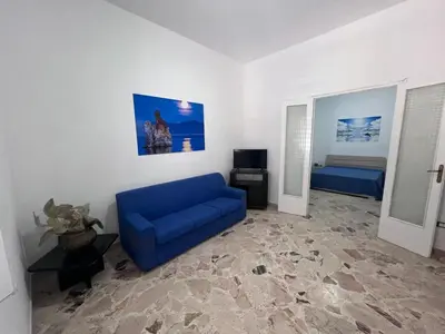 a living room with a blue couch and a bed at Casa di Pippo in Trappeto