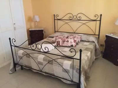a bedroom with a black bed with pink pillows at Villa Priscilla in Cinisi