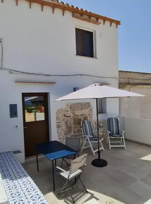 a patio with a table and an umbrella and chairs at Scopello - Finestra sul cortile in Scopello