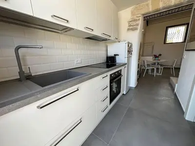 a kitchen with white cabinets and a sink and refrigerator at Scopello - Finestra sul cortile in Scopello